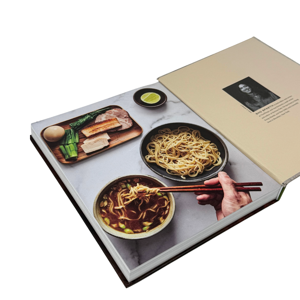 Open book showing images of noodles and a hand with chopsticks on a white background