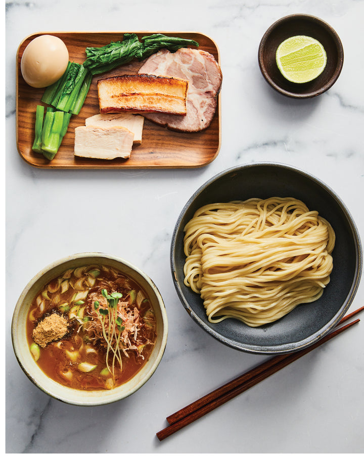 Ramen set with soup, noodles, pork, porkbelcy, ramen egg, and greens on a marble surface