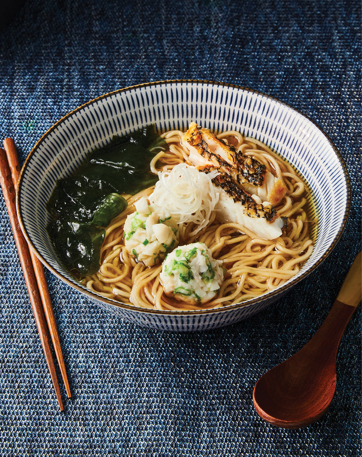 Bowl of ramen, chopsticks and spoon on a blue textured surface
