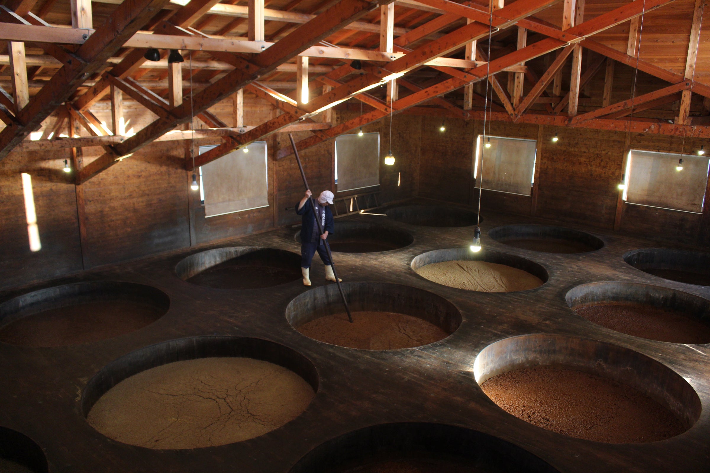 Person stirring soy sauce mash in handcrafted kioke cedar barrels
