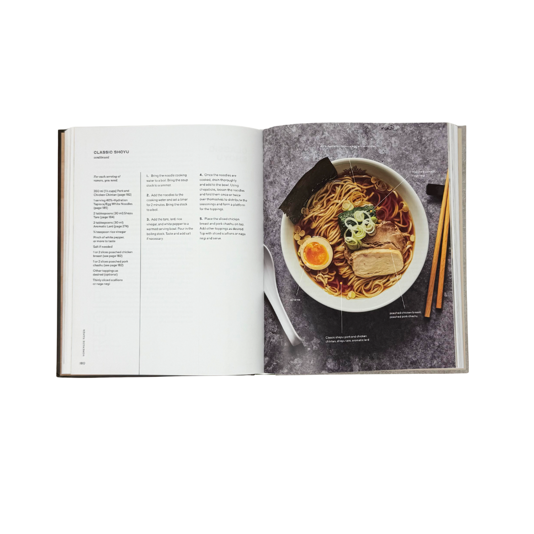 Open book showing a recipe for ramen with a bowl of noodles and chopsticks on a white background