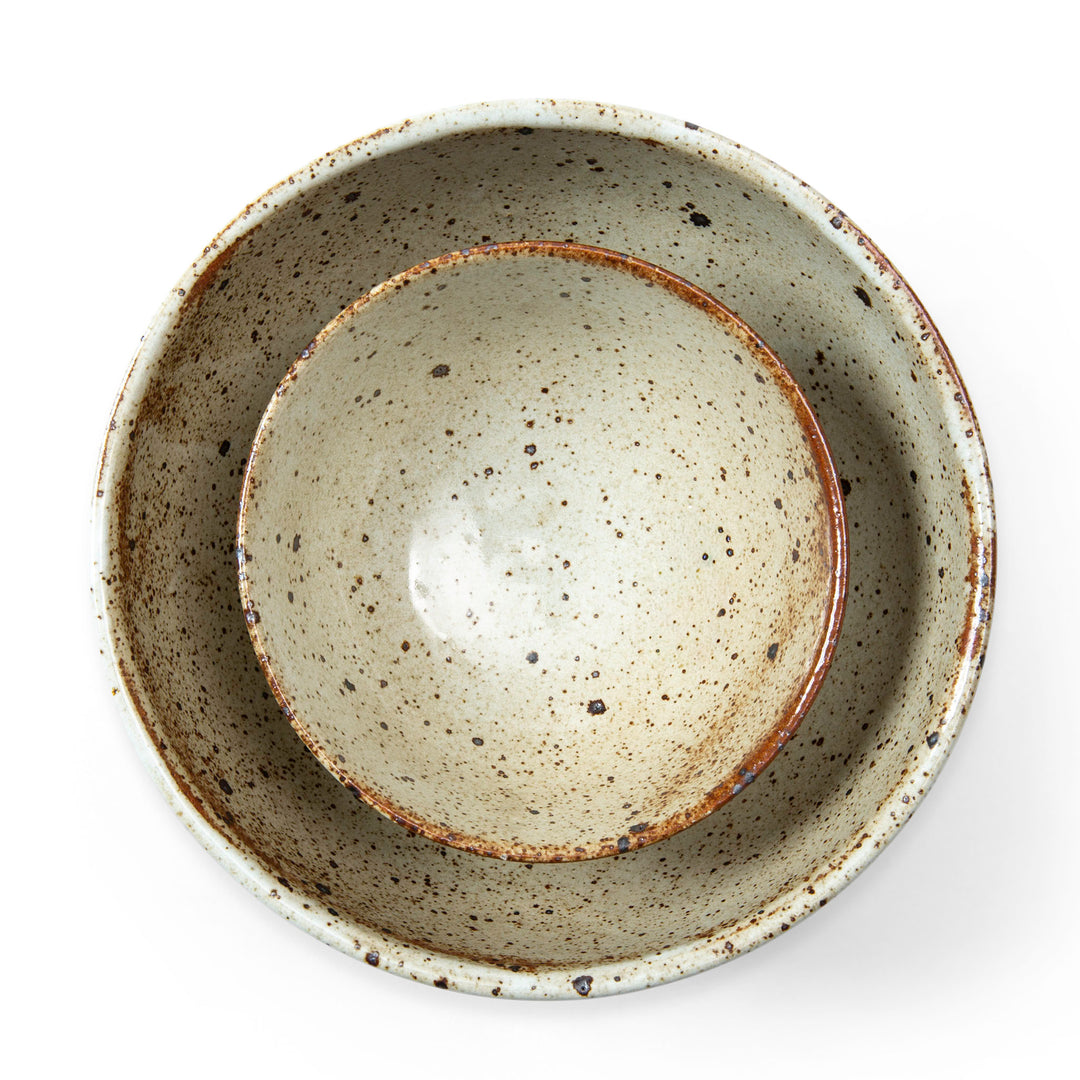 Stack of two ceramic bowls with speckled glaze on a white background