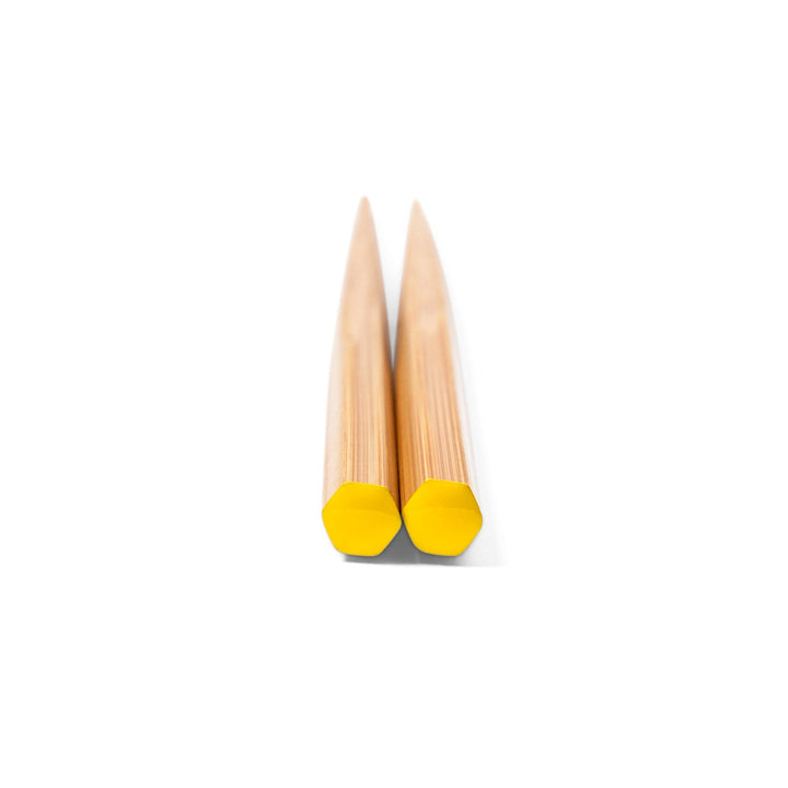 Pair of chopsticks with yellow tips on a white background