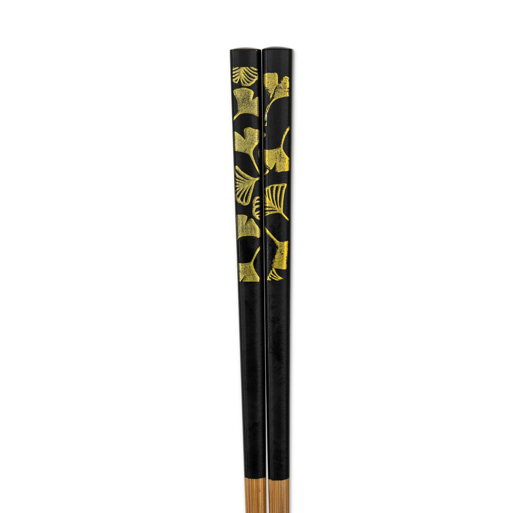 Black chopsticks with gold leaf gingko patterns on a white background