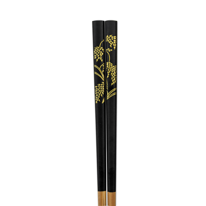 Black chopsticks with gold leaf rice stalk patterns on a white background