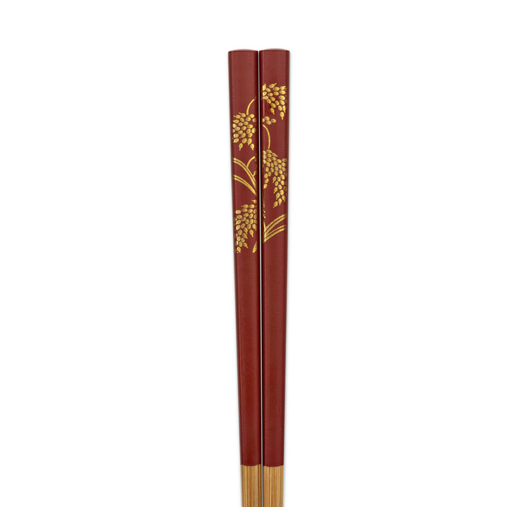 Red chopsticks with gold leaf rice stalk patterns on a white background