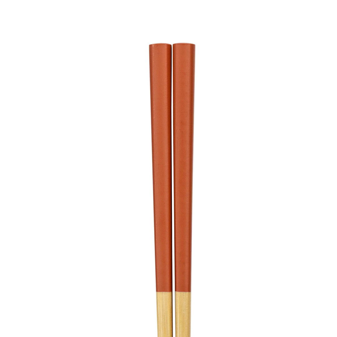 Two wooden chopsticks painted orange on a white background