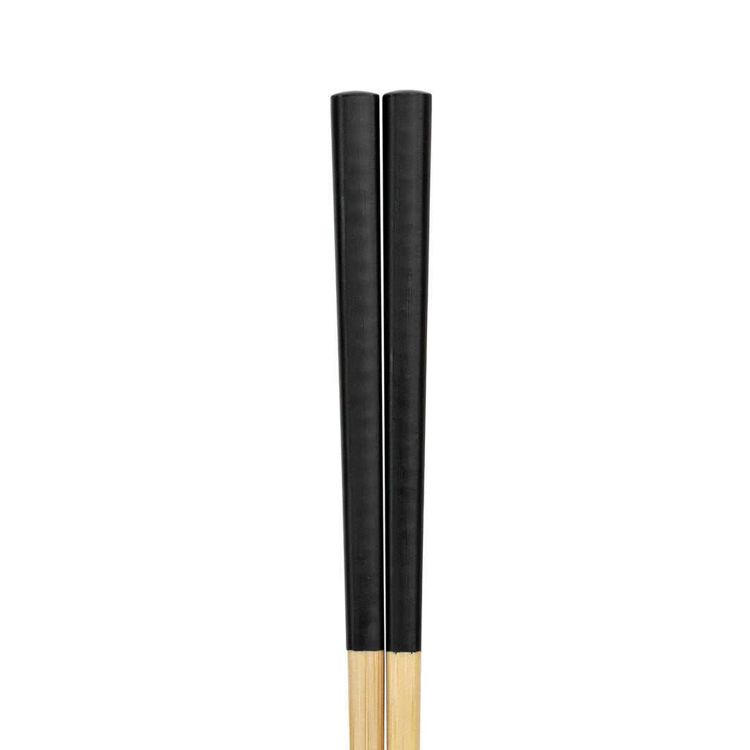 Two wooden chopsticks painted black on a white background