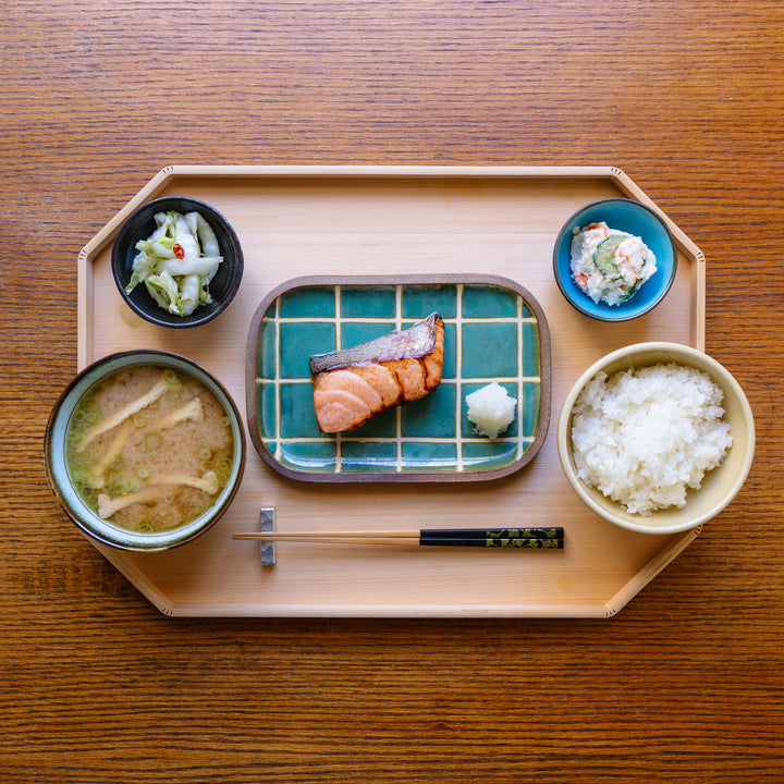 Japanese meal set on a wooden tray with salmon, rice, soup, and side dishes.