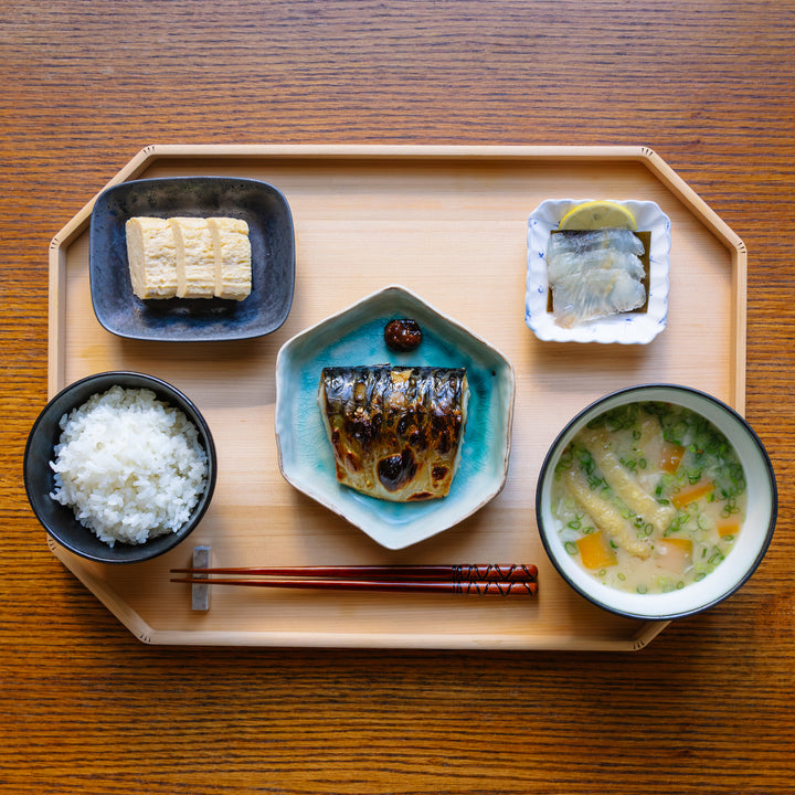Japanese meal set on a wooden tray with salmon, rice, soup, and vegetables.