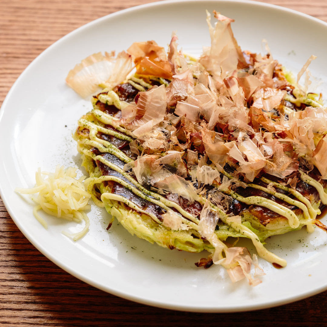 A plate with Japanese Okonomiyaki garnished with mayo and katsuobushi flakes