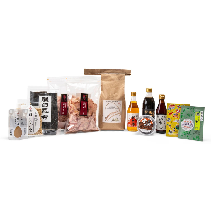 A collection of Japanese food products arranged on a white background, including packaged snacks, a brown paper bag, bottles of sauce, and boxes of sweets.