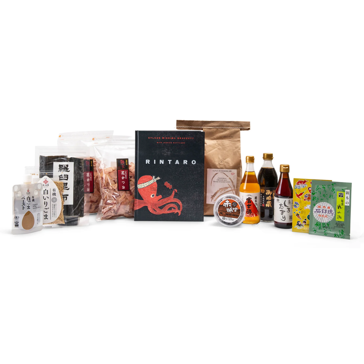 A curated Japanese food and snack assortment displayed on a white background, featuring a black RINTARO octopus box, a brown paper bag, several bottles of sauces and condiments, packaged snacks, and small boxes with Japanese text.