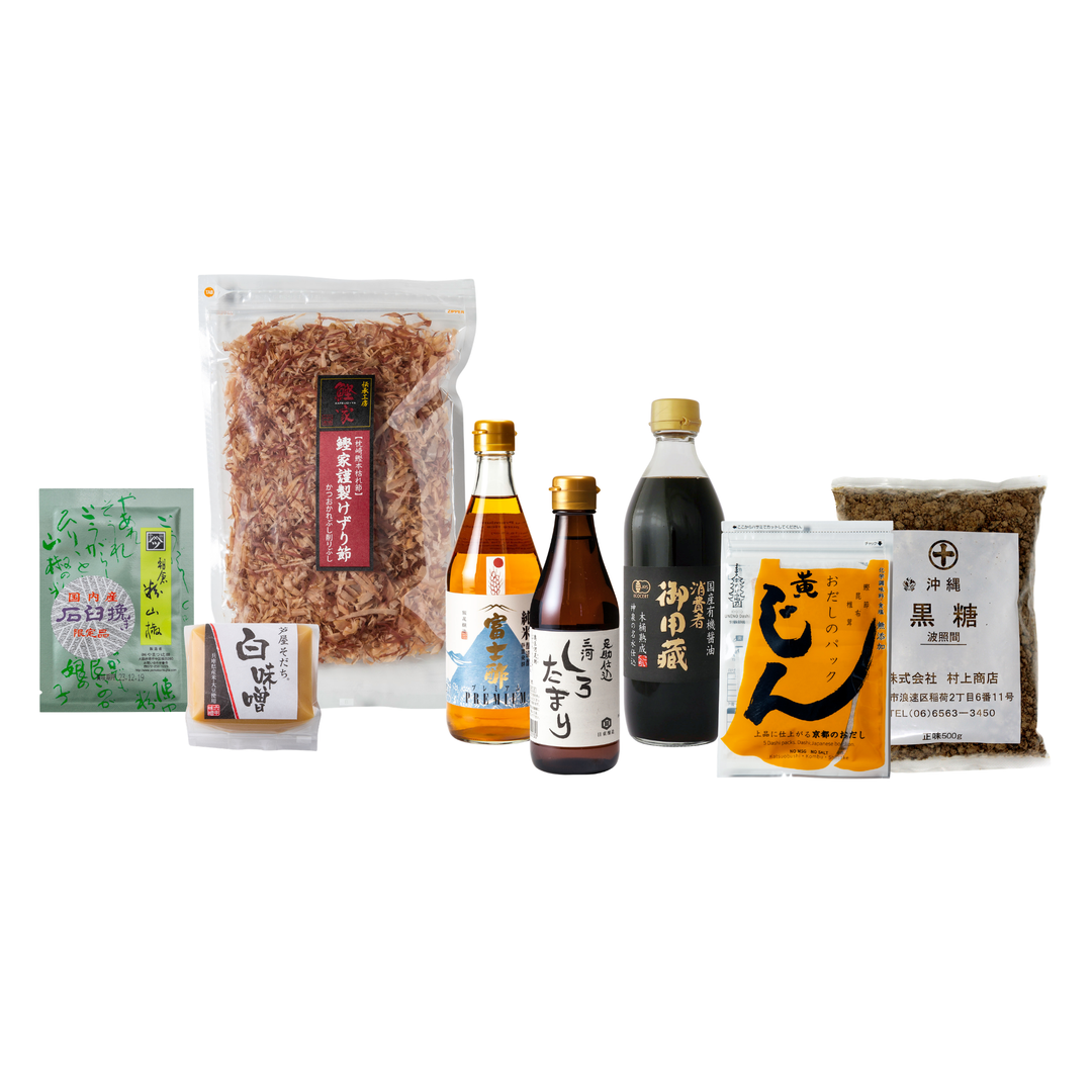 A collection of Japanese food products arranged on a white background, including a large bag of dried shredded ingredients, two bottles of soy sauce, a small packaged item, and two bags of seasoning or spice blends.