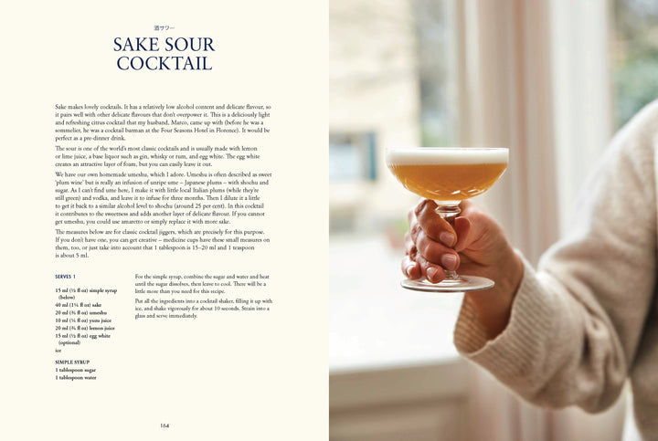 Hand holding a glass of sake sour cocktail with recipe on left side.