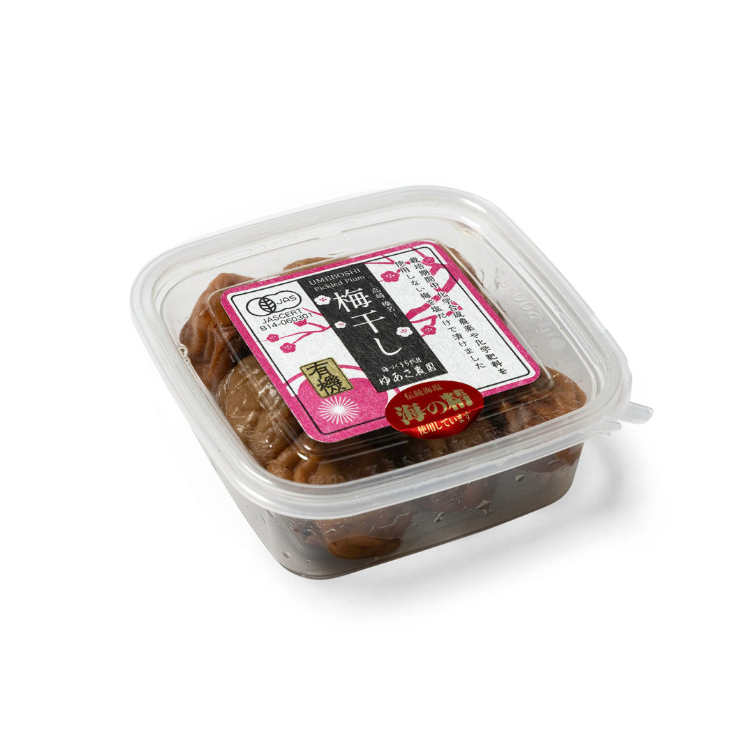 A clear plastic container of Japanese plum jam (ume paste) with a pink and black label, photographed on a clean white background.
