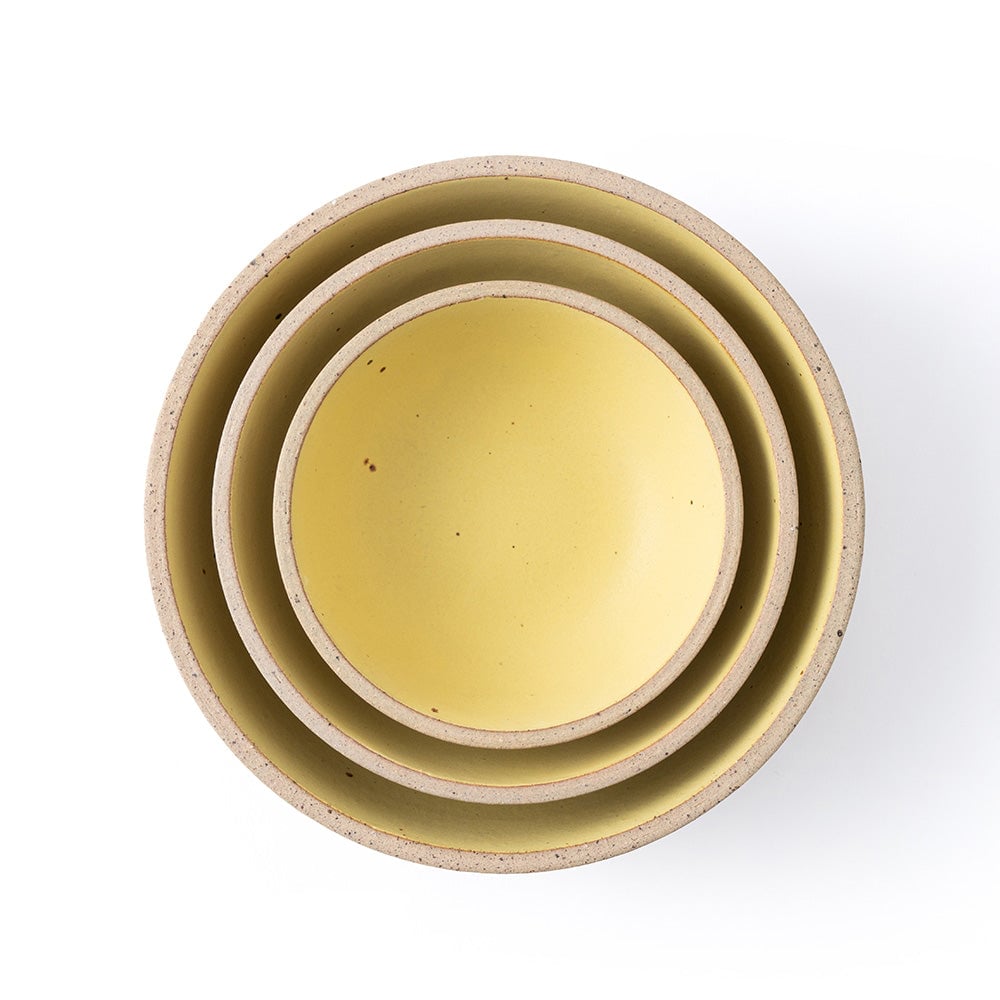Set of three ceramic bowls in yellow and beige on a white background