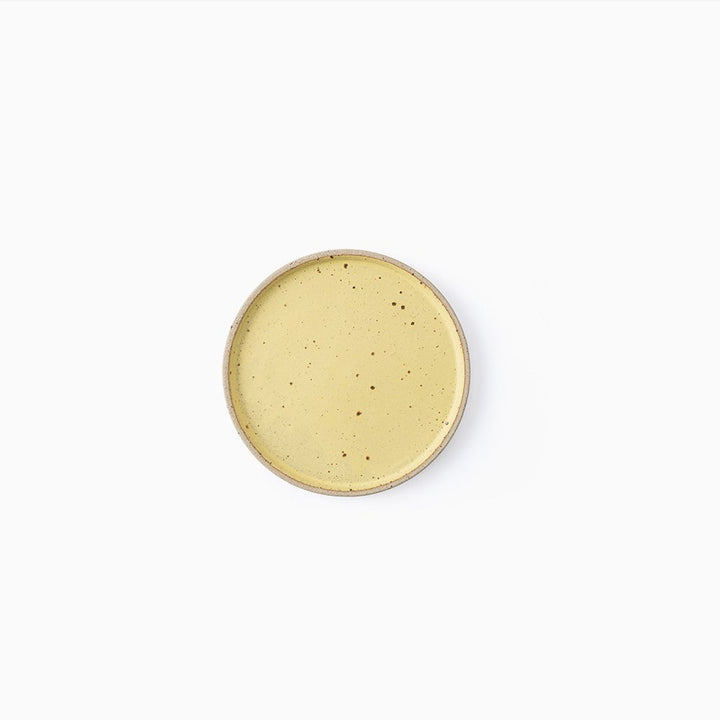 A round ceramic plate with a speckled light yellow glaze and a natural beige rim, photographed from directly above on a solid white background.