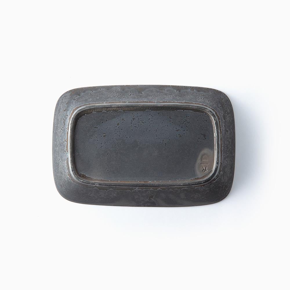 Botton of black mottled rectangular ceramic bowl on a white background
